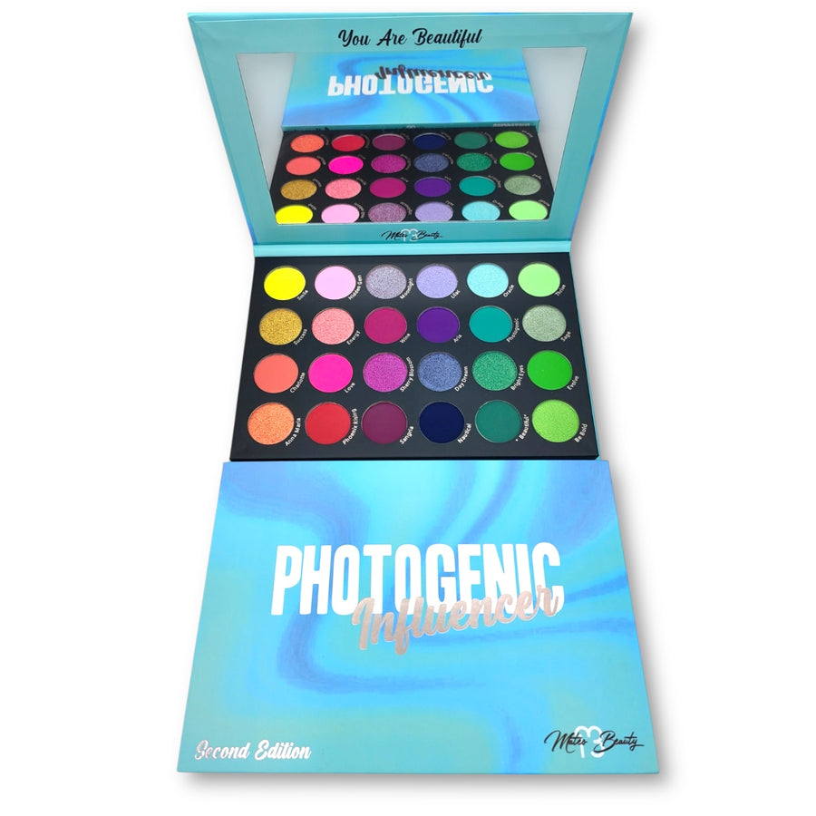 Photogenic Second Edition palette open to show 24 colorful eyeshadows and a mirror, with turquoise packaging in front.